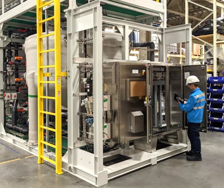 Photo of a Saltworks employee inspecting the electrical panel in a BrineRefine chemical reactor plant